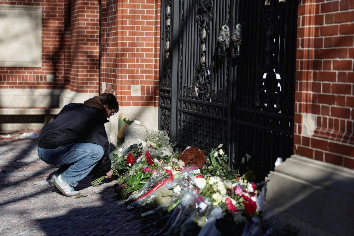 A student leaves flowers in front of the Van Wickle Gates as the manhunt continues for the gunman, following a shooting at Brown University in Providence, Rhode Island, U.S. December 15, 2025.  REUTERS/Taylor Coester