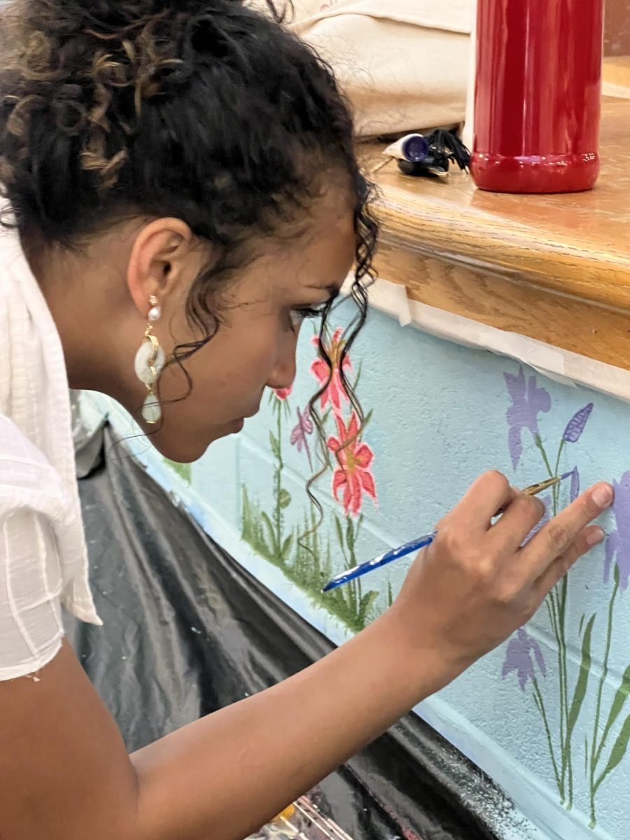 Senior Alexandra Chleboski works on the flower- themed mural in our foyer.